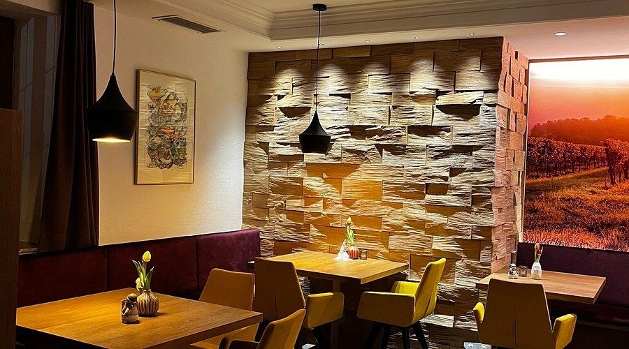 Gastraum von arbor's wine & bistro mit Natursteinwand, Holztischen und gelben Stühlen